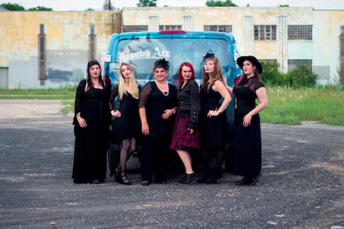 All the tour guides dressed up in spooky attire in front of the public van