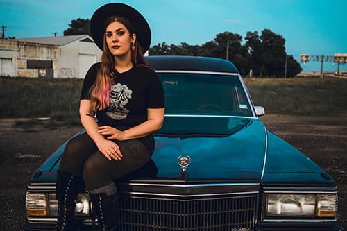 Female model repping Haunted ATX shirt while sitting on black hearse