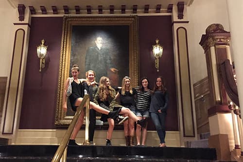 A girls party standing in front of a portrait in a hotel